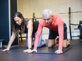 Senior man exercising on a mat with a woman trainer