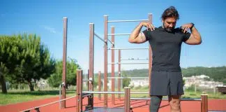 The Ultimate Guide to Shoulder Mobility Exercises: Improve Your Range of Motion and Reduce Pain A man touching his shoulders while standing near the wooden platform